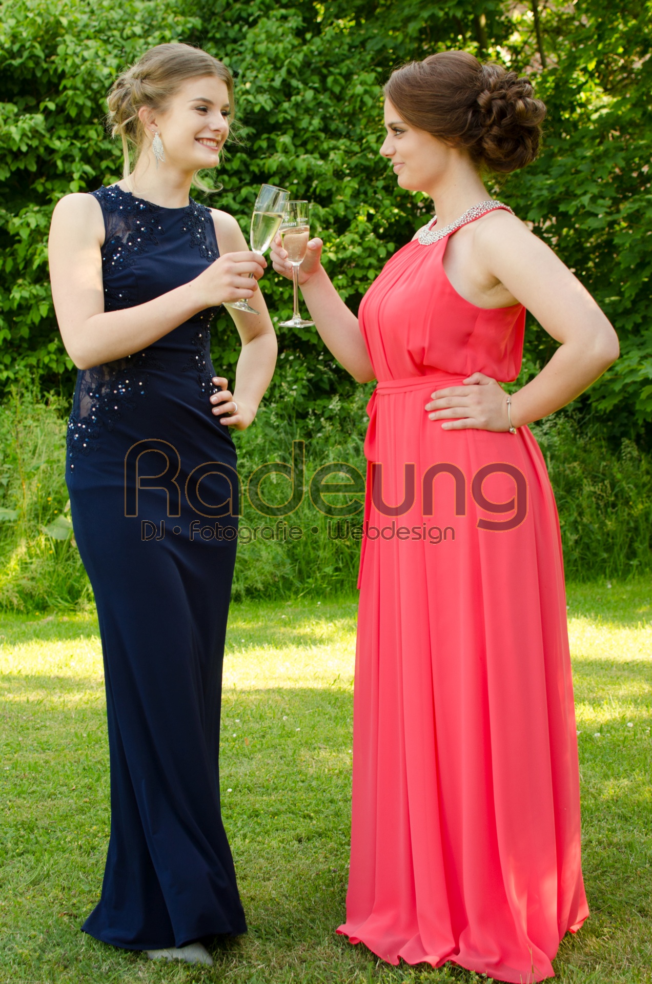 Zwei junge Damen stoßen auf ihrer Abschlussfeier miteinander an.